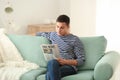 Handsome man reading newspaper on sofa at home Royalty Free Stock Photo