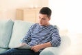 Handsome man reading newspaper on sofa at home Royalty Free Stock Photo