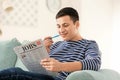 Handsome man reading newspaper on sofa at home Royalty Free Stock Photo