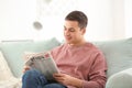 Handsome man reading newspaper on sofa at home Royalty Free Stock Photo