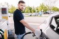 Handsome man refuelling his car on self service gas station. Filling diesel at gasoline fuel in car using a fuel nozzle. Royalty Free Stock Photo