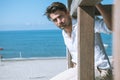 Handsome man relaxed at the sea, overlooking a wooden structure. Sea and blue sky.