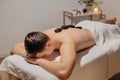 Handsome man relaxing during back massage with hot stones. Body care and SPA in resort Royalty Free Stock Photo
