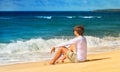 Handsome Man relaxing on the Beach sitting on seaside sand and looking on Sea waves Summer time Royalty Free Stock Photo