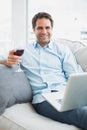 Handsome man relaxing on sofa with glass of red wine using laptop Royalty Free Stock Photo