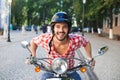 Handsome man riding a scooter on city streets Royalty Free Stock Photo