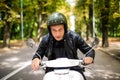 Handsome man riding a scooter on city streets on summer day. Closeup portrait of happy smiling young male on vintage scooter Royalty Free Stock Photo