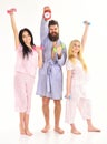 Handsome man in robe, trainer holds clock, attractive young women in pajamas doing exercises with dumbbells, bodybuilder