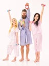 Handsome man in robe, trainer holds clock, attractive young women in pajamas doing exercises with dumbbells, bodybuilder