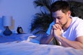 Handsome man saying bedtime prayer in dark room. Space for text Royalty Free Stock Photo
