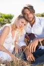 Handsome man serenading his girlfriend with guitar smiling at camera