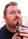 An Handsome man shaving face with electric razor Royalty Free Stock Photo