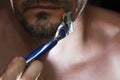 Handsome man shaving his beard with razor in bathroom. Daily cosmetic procedure, facial skin care concept Royalty Free Stock Photo