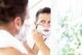 Handsome man shaving his beard while standing in front of a mirror Royalty Free Stock Photo