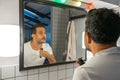 Handsome man is shaving his beard with trimmer machine in front of bathroom mirror Royalty Free Stock Photo