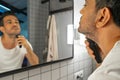 Handsome man is shaving his beard with trimmer machine in front of bathroom mirror Royalty Free Stock Photo