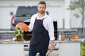 Handsome man in shirt and in cook apron preparing fish on barbecue. Grilling salmon outdoor. Male cook cooking salmon Royalty Free Stock Photo