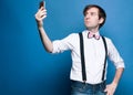 handsome man in shirt with rolled up sleeves and black suspender standing and taking selfie