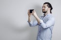 Handsome man in a shirt. takes on the phone. Long hair. Gray background