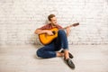 Handsome man siting on floor and playing on the guitar Royalty Free Stock Photo