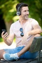 handsome man sitting on bench outdoors and using smartphone Royalty Free Stock Photo