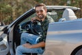 Handsome man sitting in the car with open door and smiling at the camera Royalty Free Stock Photo