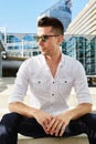 Handsome man sitting in city with sunglasses Royalty Free Stock Photo