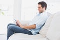 Handsome man sitting on the couch using his tablet Royalty Free Stock Photo