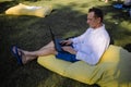 Handsome Man Sitting On The Grass In The City With A Laptop And Talking On Phone Royalty Free Stock Photo