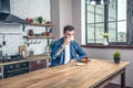 Handsome man is sitting at the kitchen having his morning coffee with croissant and an apple juice Royalty Free Stock Photo
