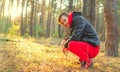Handsome man sitting posing in the woods at sunrise. A man in a red tracksuit and a black leather jacket Royalty Free Stock Photo