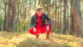 Handsome man sitting posing in the woods at sunrise. A man in a red tracksuit and a black leather jacket Royalty Free Stock Photo