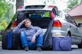 Man sitting on the road next to car with open trunk