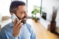 A man with a smartphone making a phone call at home.