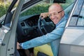 Handsome man smile on face closing door of his car, hands on wheel