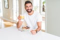 Handsome man smiling eating healthy breakfast and drinking orange juice in the morning Royalty Free Stock Photo