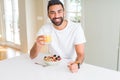 Handsome man smiling eating healthy breakfast and drinking orange juice in the morning Royalty Free Stock Photo