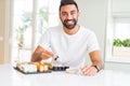 Handsome man smiling happy enjoying eating fresh colorful asian sushi using chopsticks Royalty Free Stock Photo