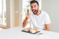 Handsome man smiling happy enjoying eating fresh colorful asian sushi using chopsticks Royalty Free Stock Photo