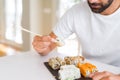 Handsome man smiling happy enjoying eating fresh colorful asian sushi using chopsticks Royalty Free Stock Photo