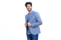 Handsome man standing in blue blazer smiling by white wall