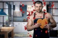 Handsome man standing in the kitchen with a biscuit heart in his hands. rose petals falling on the man. A man is dressed in an apr Royalty Free Stock Photo