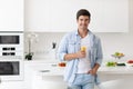 Handsome man standing on the kitchen and drinking orange juice Royalty Free Stock Photo