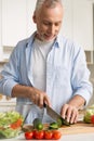 Handsome man standing at the kitchen using laptop and cooking Royalty Free Stock Photo