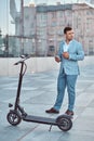 Handsome man is standing near his electro scooter