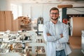 Handsome man is standing and smiling. Print house worker in white clothes is indoors Royalty Free Stock Photo