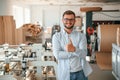 Handsome man is standing and smiling. Print house worker in white clothes is indoors Royalty Free Stock Photo