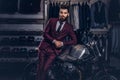 Handsome man with a stylish beard and hair dressed in vintage red suit posing near retro sports motorbike at men`s Royalty Free Stock Photo