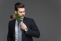 handsome man in suit holding red rose in mouth, Royalty Free Stock Photo