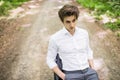 Handsome man in suit sitting on office chair on road in green forest. Business concept Royalty Free Stock Photo